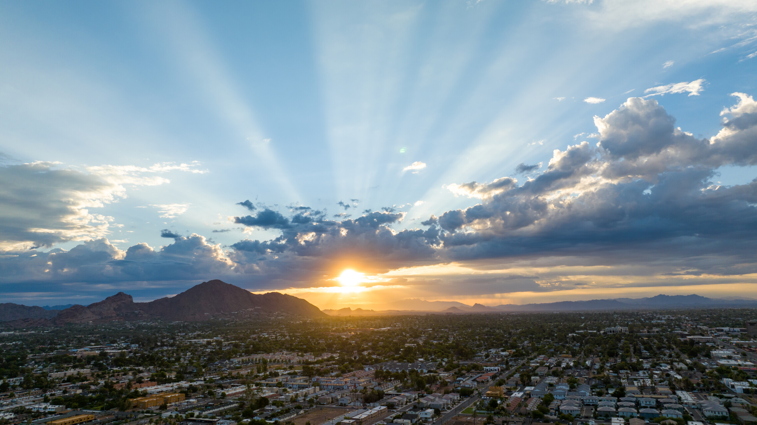 Golden sunrise with light rays piercing through clouds over Camelback Mountain, symbolizing Phoenix's digital dawn.